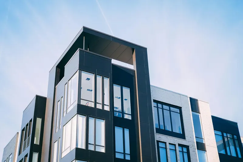 Black and white apartment block with deep window reveals against blue sky